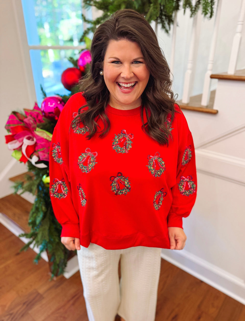 red sweatshirt with sequin wreaths on thr front 