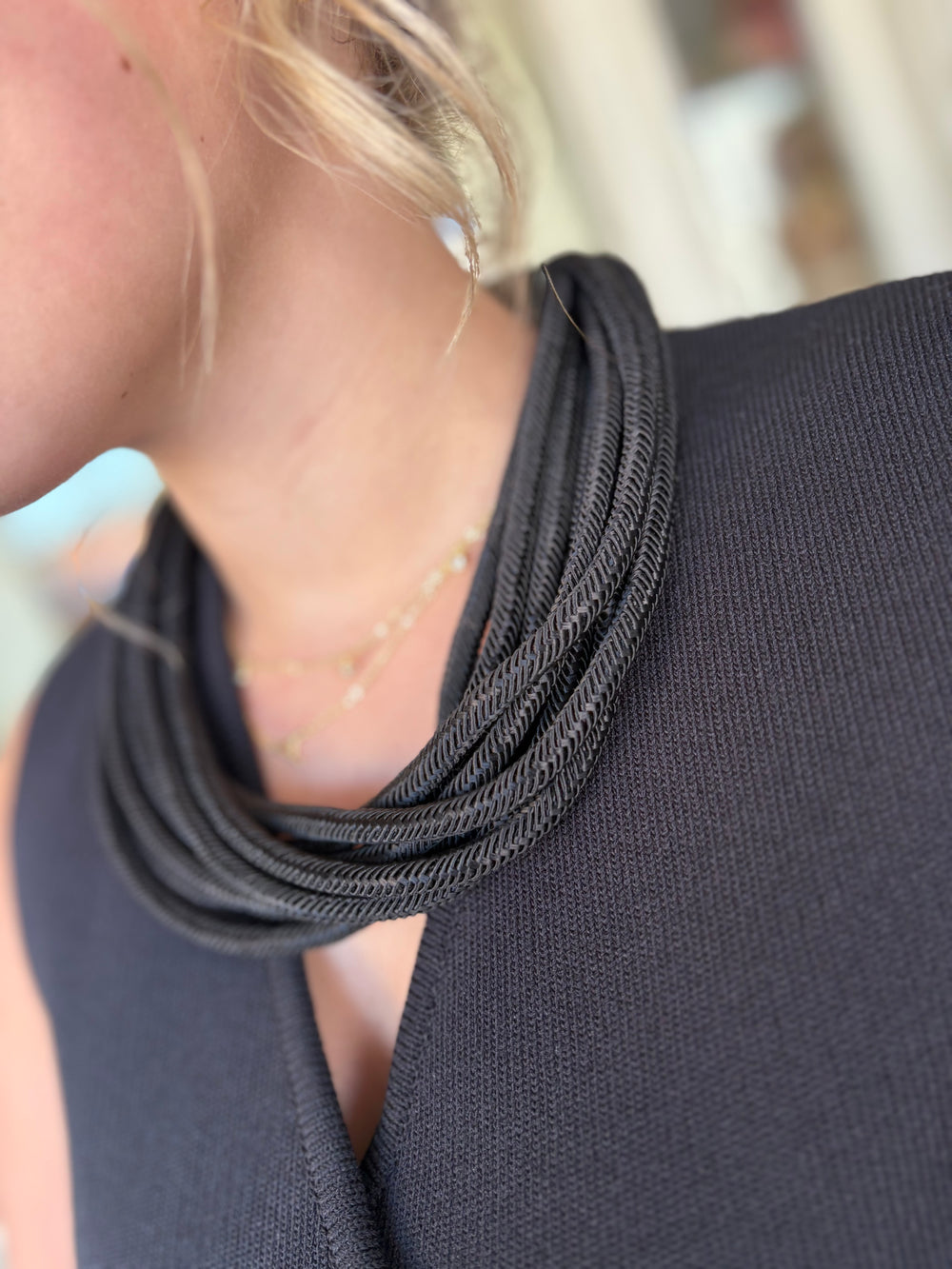 Close-up of a person wearing a dark gray scarf with a blurred background