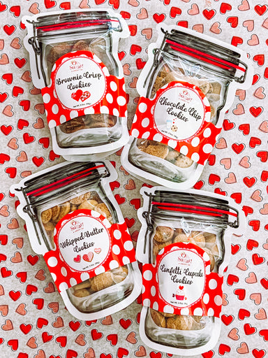 Four packages of cookies with red and white labels on a heart-patterned background