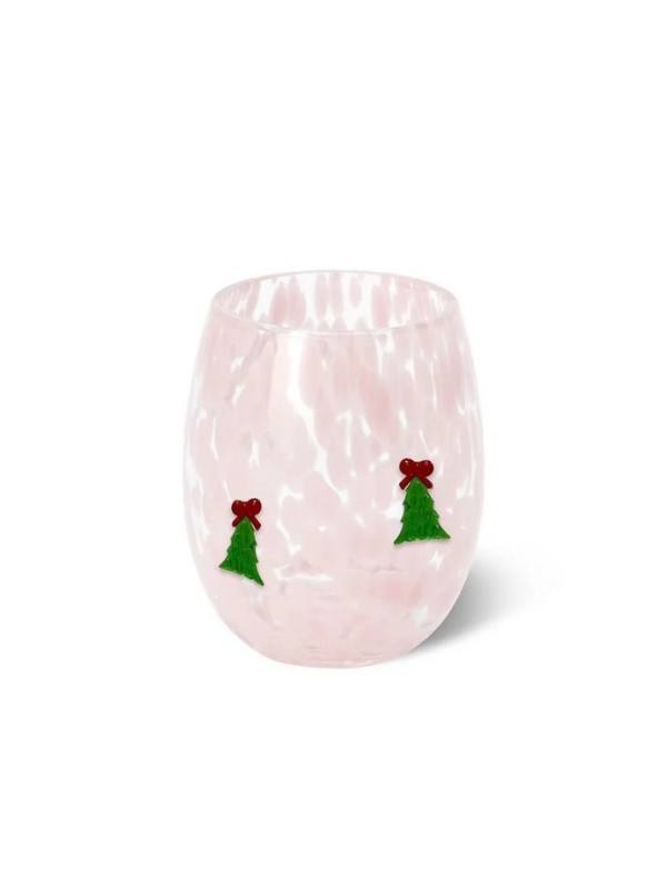 A light pink stemless wine glass with a textured, hammered finish, decorated with two small green Christmas tree ornaments with red bows near the lower front, set against a plain white background.