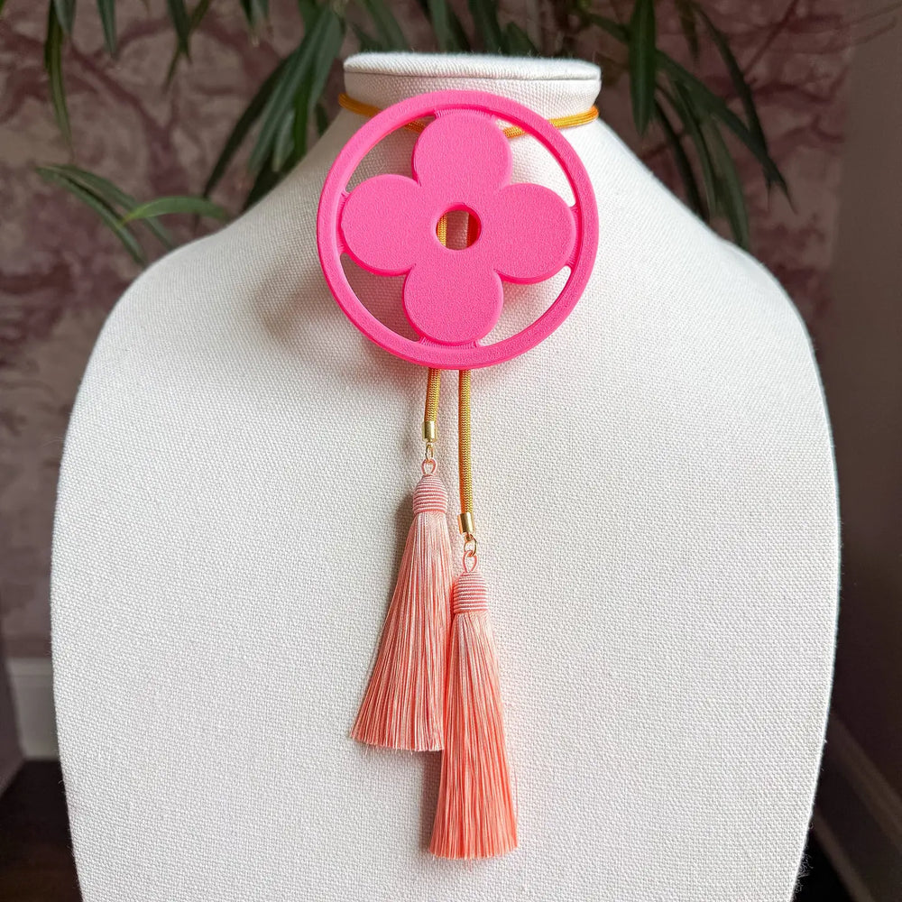  A geometric clover takes center stage, framed like a statement medallion and designed to turn even the simplest outfit into a full look. 