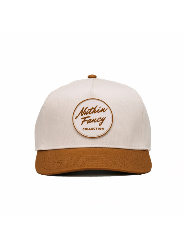 A baseball cap with an off-white crown and a brown curved brim, featuring a circular brown logo patch on the front that reads 'Nuthin Fancy COLLECTION'.