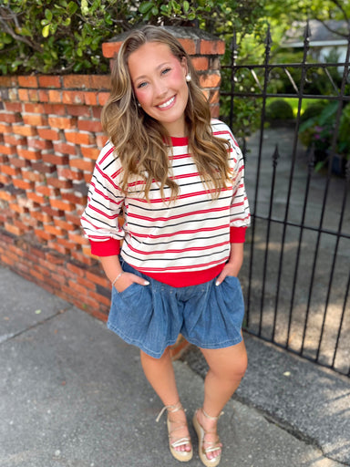 A red and white striped long-sleeve top thin black striped and red trim