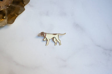 A small dog pin in gold-tone metal with a cream enamel fill