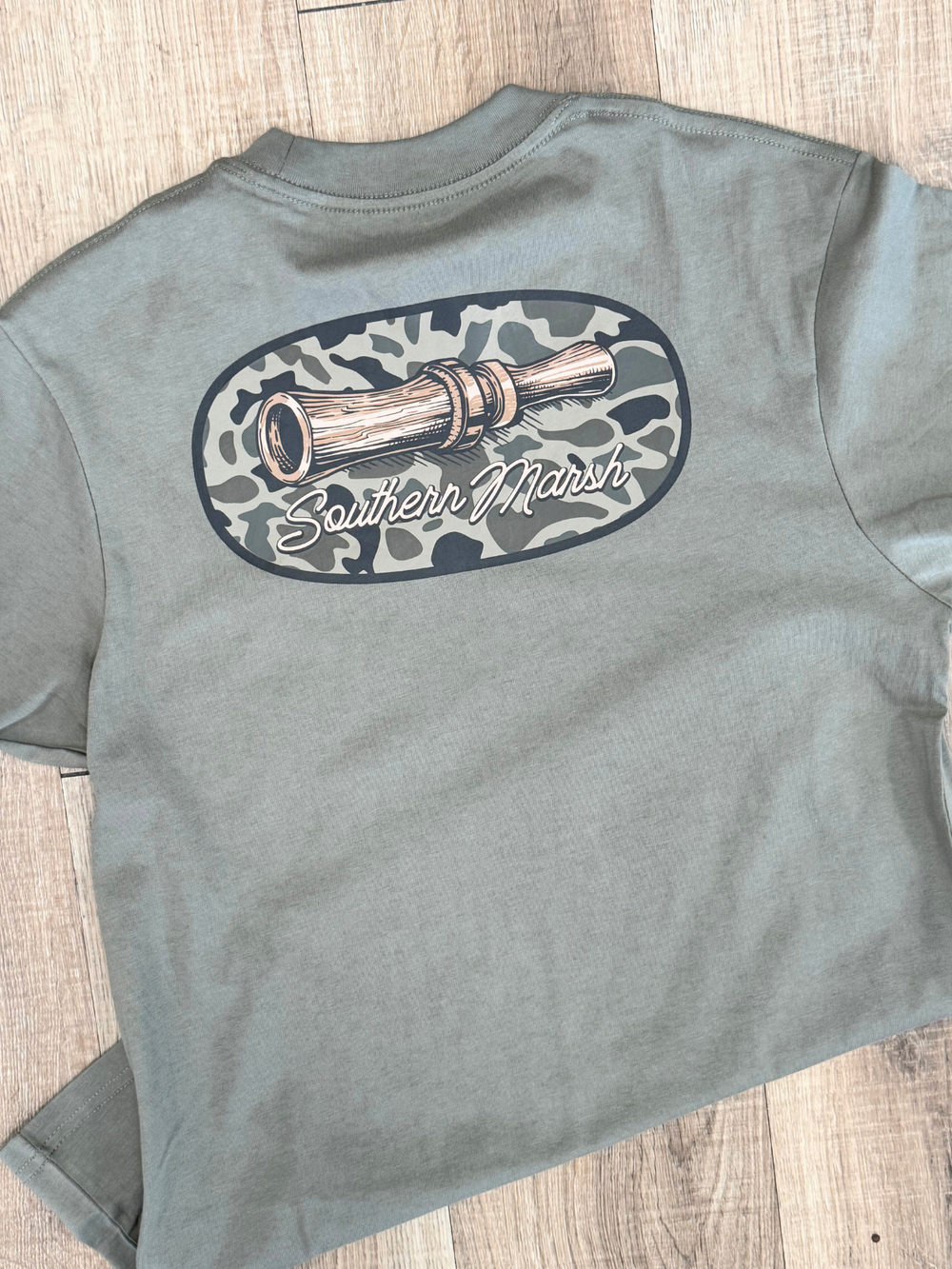 duck call in a camo oval on a green shirt