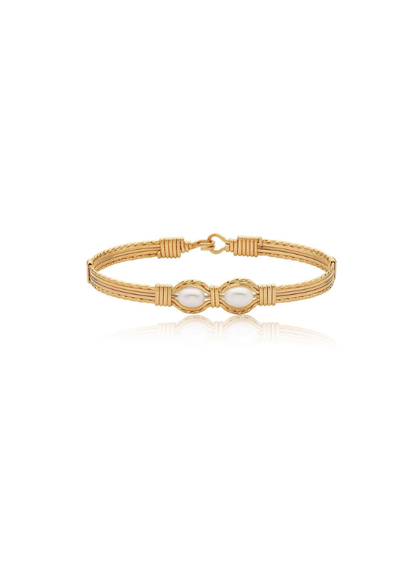Gold bracelet with a central pearl on a white background