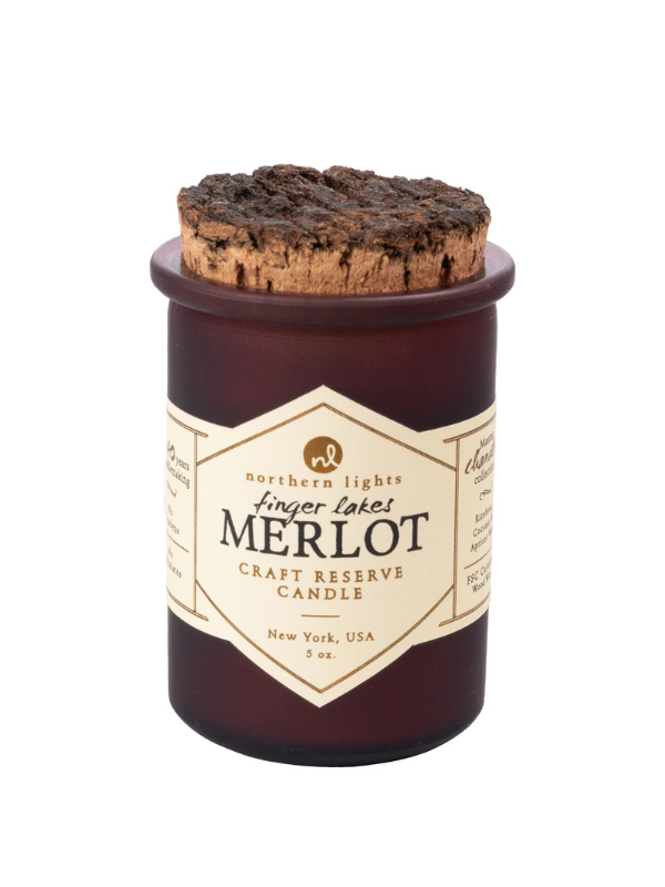A brown glass jar candle with a cork lid, labeled 'Finger Lakes Merlot Craft Reserve Candle', with a wood wick