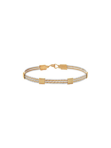 Gold bracelet with a white cord on a white background