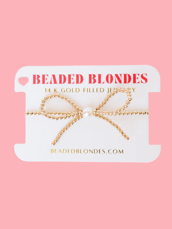 A gold bow beaded bracelet with a pearl in the middle