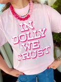 In Dolly We Trust. This light pink graphic tee features bold white lettering outlined in hot pink with fun little star details throughout.