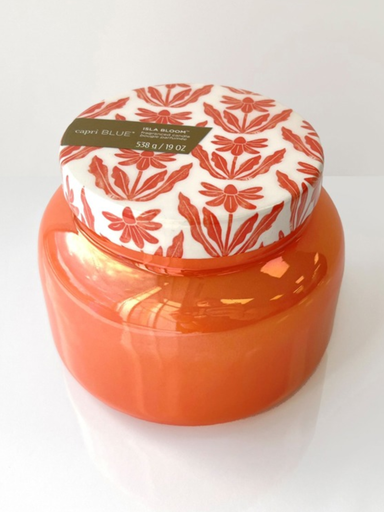 Orange glass Isla Bloom Riviera Sunset Signature Candle (19 oz) with a white lid featuring a bold coral floral pattern, shown on a white background.