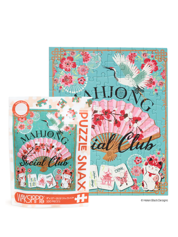 A packaged jigsaw puzzle and its box shown on a white background. The puzzle artwork features a turquoise background with pink cherry blossoms, a pink folding fan, white cranes, playing cards, and a white cat, with the words 'MAHONG Social Club' and 'PUZZLE Club'.