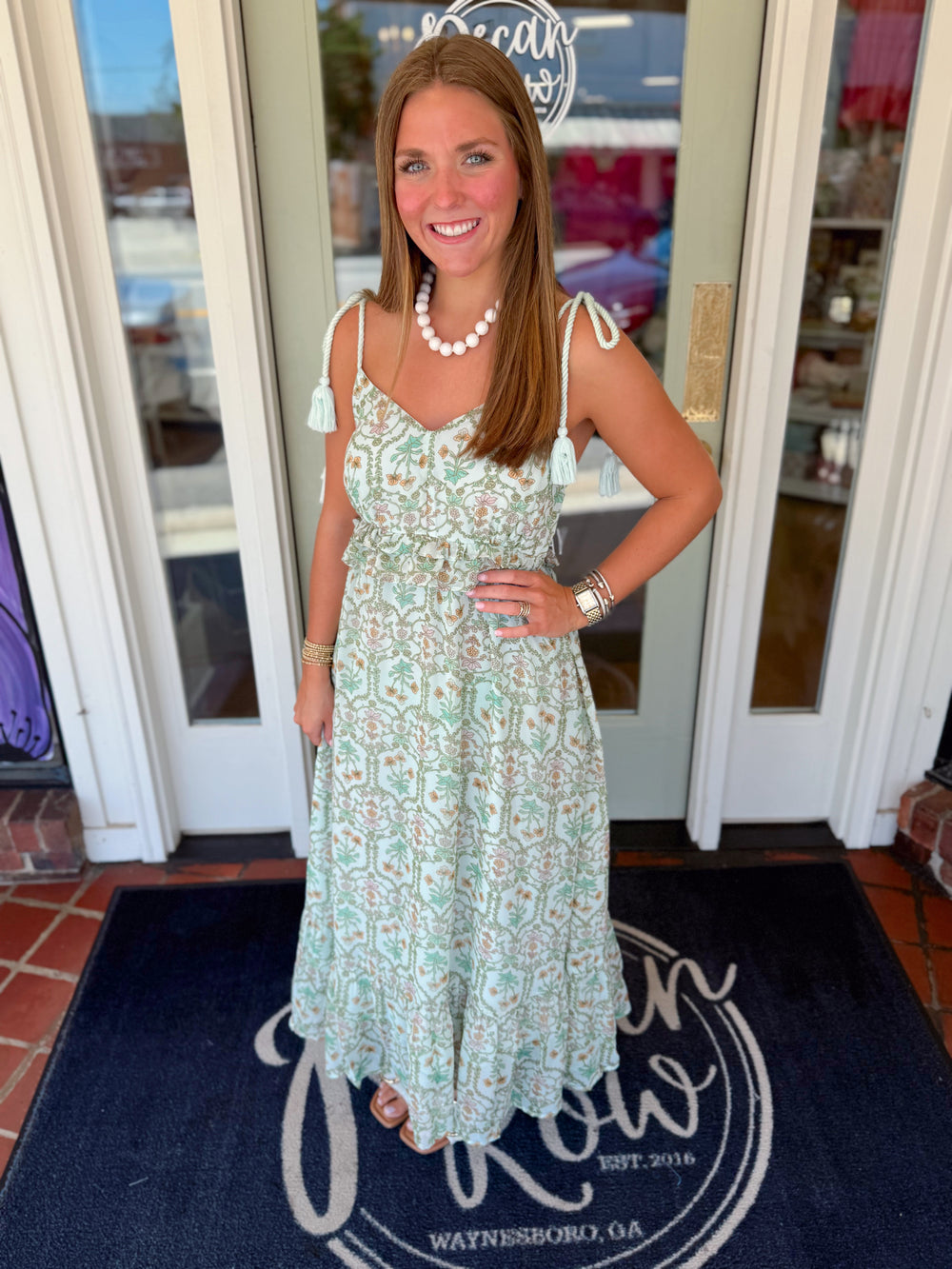 Mint green floral maxi dress featuring adjustable rope shoulder ties with tassels, a smocked waist, feminine neckline, and a flowing tiered skirt.