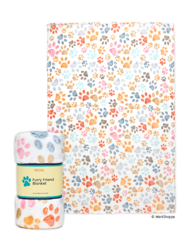 A multicolor paw print patterned blanket shown flat with a matching rolled blanket and paper band in front, on a plain white background. The paper band reads 'Furry Friend Blanket' and shows the WerksShop brand.