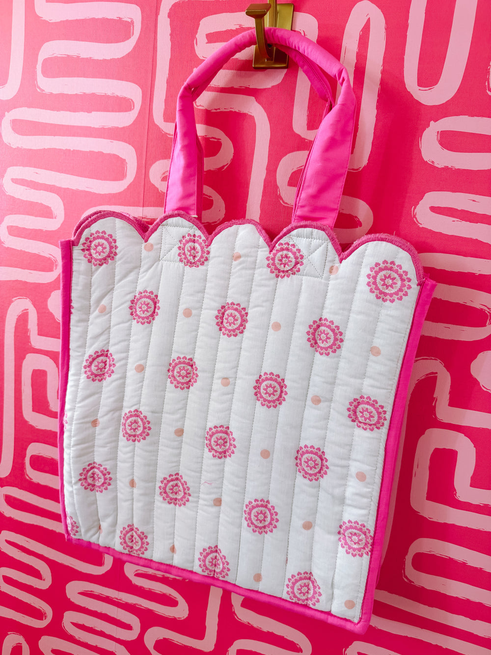 White baby blanket with pink floral pattern in a pink frame against a pink background