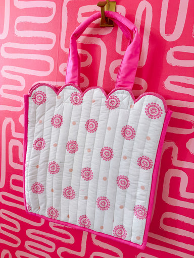 White baby blanket with pink floral pattern in a pink frame against a pink background
