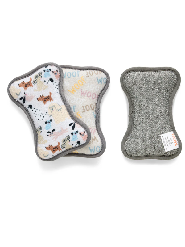 Two bone-shaped dog training mats on a white background, one showing a multicolor dog pattern on a cream background and the other showing a gray textured side with a small white brand tag.