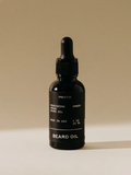 Black beard oil bottle with dropper on a beige background