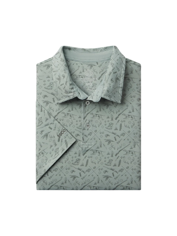 Sage green polo with guns, ducks antlers and dogs printed on it 