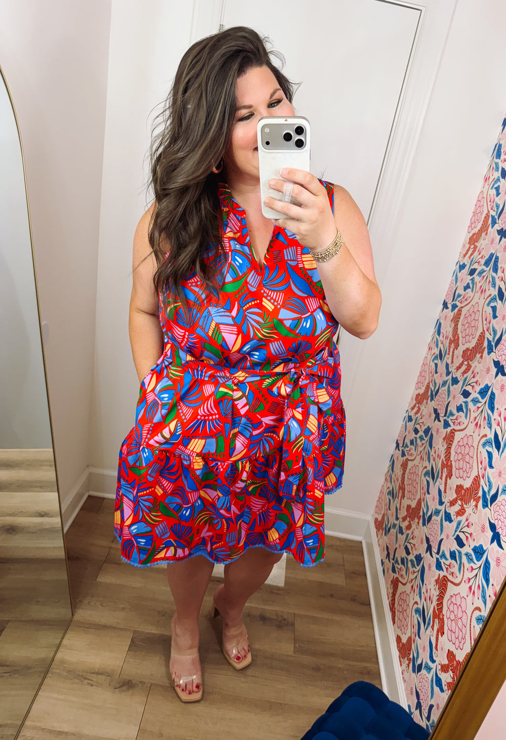 Colorful sleeveless mini dress featuring a vibrant tropical print in coral, blue, pink, green, and orange, with a self-tie waist, tiered skirt, and side pockets.