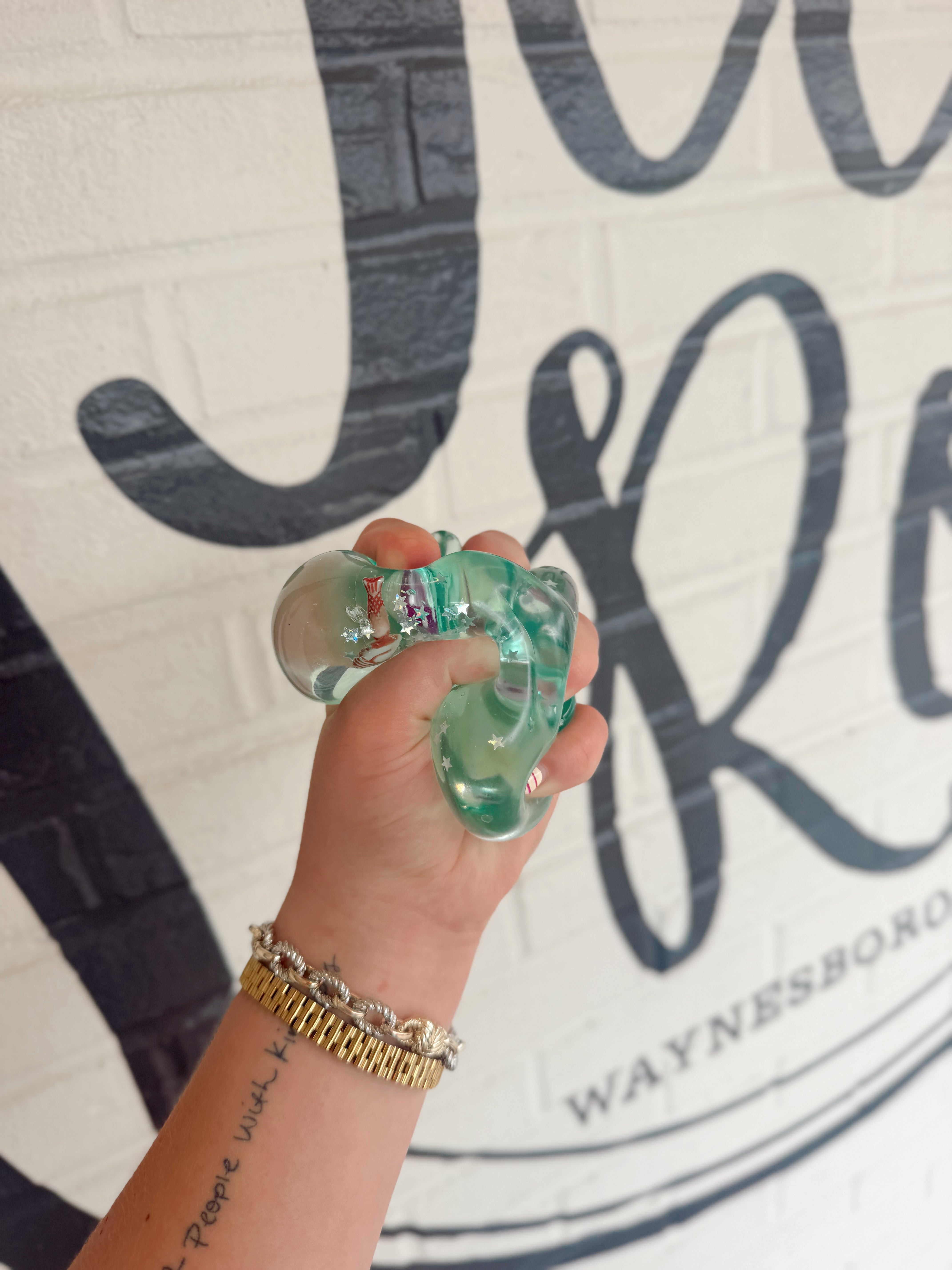 Clear sea life squishy toy filled with glitter and miniature ocean creatures inside for sensory play and stress relief.