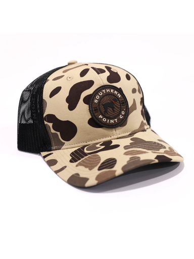 Southern Point Co. camouflage trucker hat with black mesh back and round bird dog logo patch on the front.