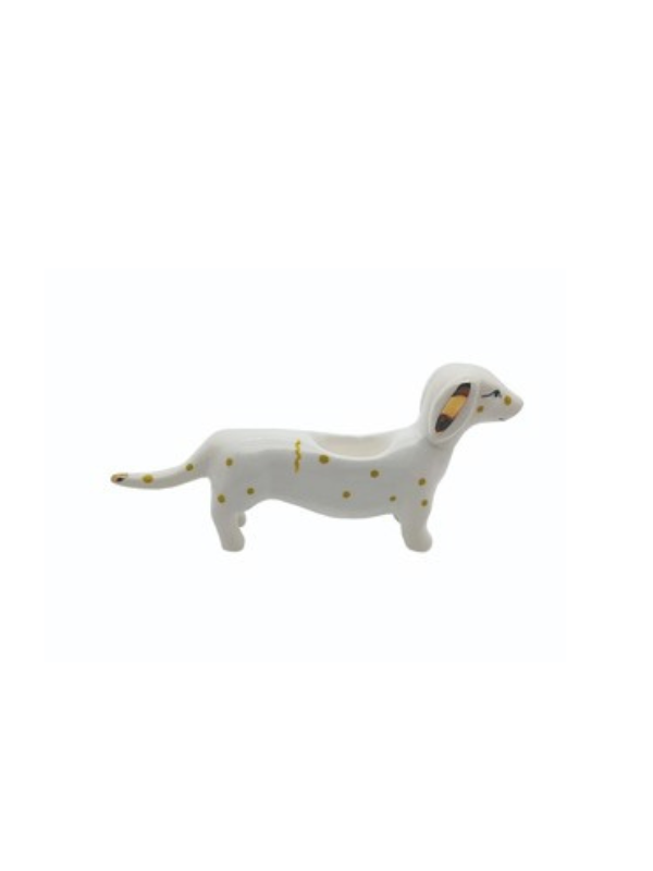 White ceramic dog figurine with yellow spots on a white background