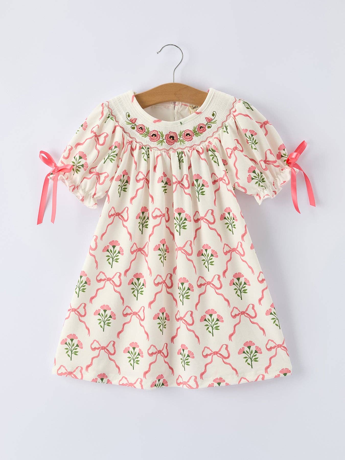 Children's dress with floral and bow pattern.