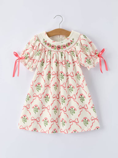 Children's dress with floral and bow pattern.