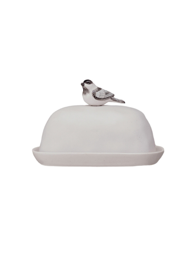 A white ceramic butter dish with a domed lid topped by a small bird figurine