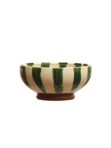 A handmade ceramic bowl with vertical hand-painted green stripes on a cream-colored glaze, resting on a small brown wooden base against a plain white background.