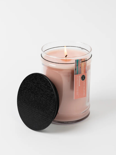 Pink candle in a glass jar with a black wooden lid 