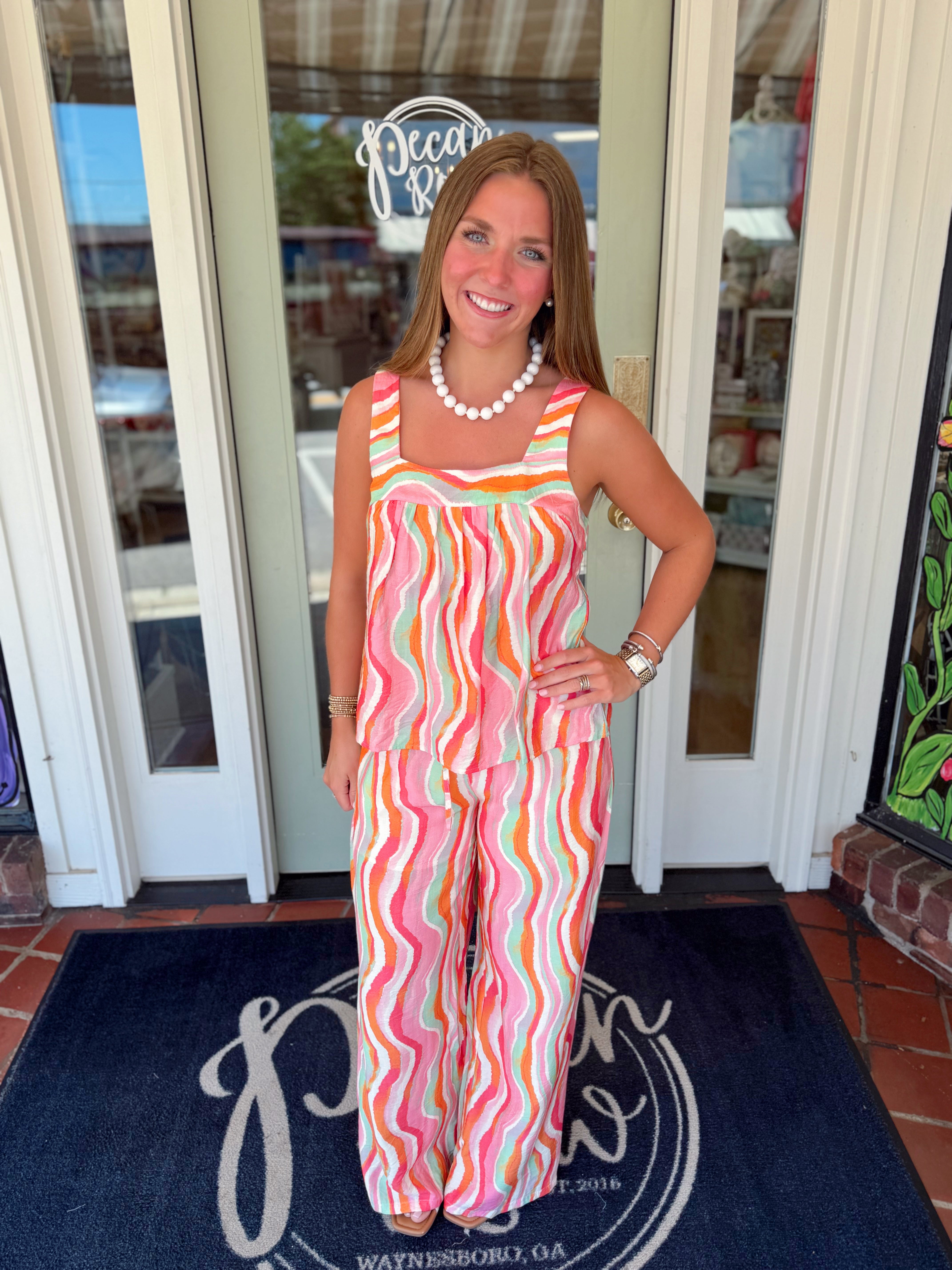 Sleeveless tank top featuring a colorful watercolor wave print in shades of pink, coral, orange, and mint with a square neckline and relaxed fit.