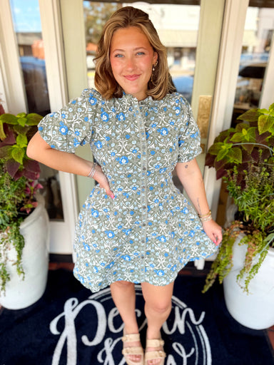 This short dress features a pretty mix of green, blue and cream florals with a classic button-down front and subtle puff sleeves for just a touch of feminine shape
