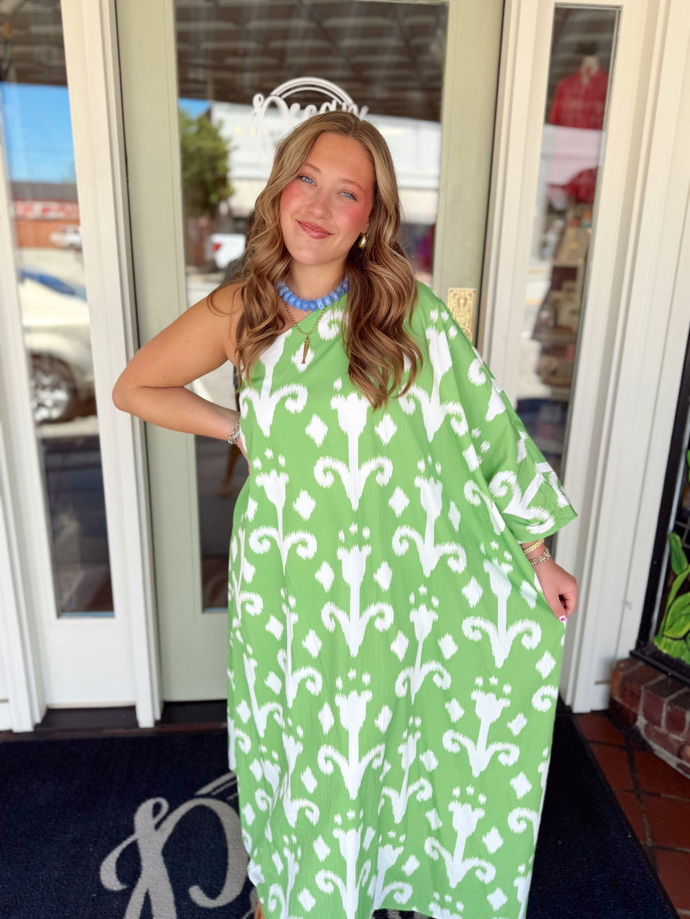 Green and white one-shoulder maxi dress with abstract print and flowy relaxed silhouette.
