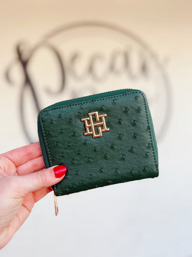 A green dot textured zip wallet with a gold CH on the front of it
