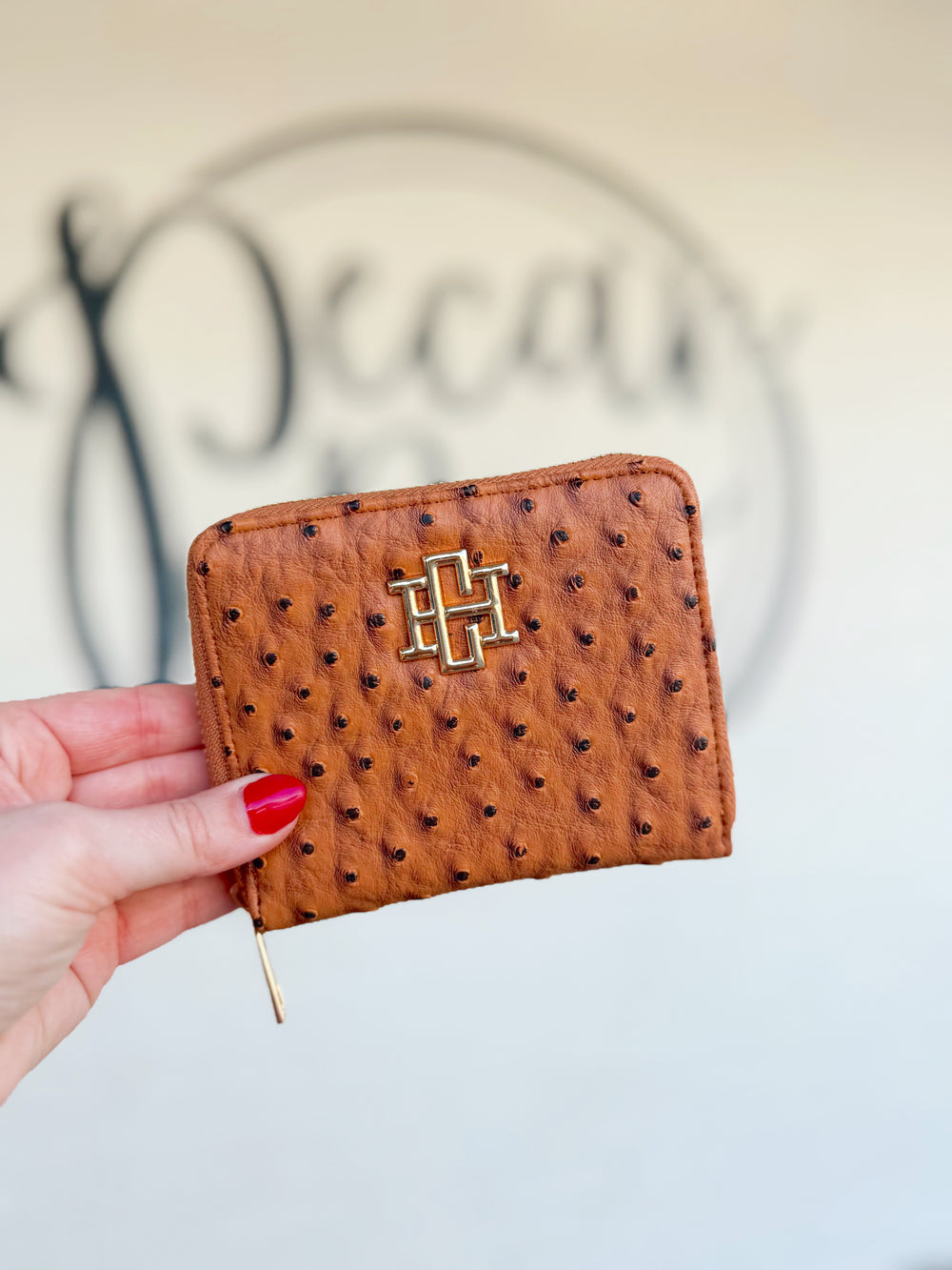 A brown textured zip wallet with a gold CH on the front 