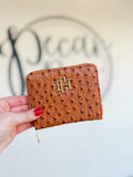 A brown textured zip wallet with a gold CH on the front 