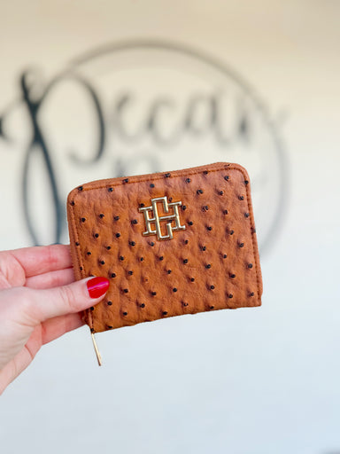 A brown textured zip wallet with a gold CH on the front 