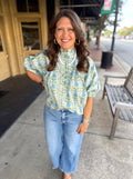 A light green and blue floral patterned blouse with puff sleeves.