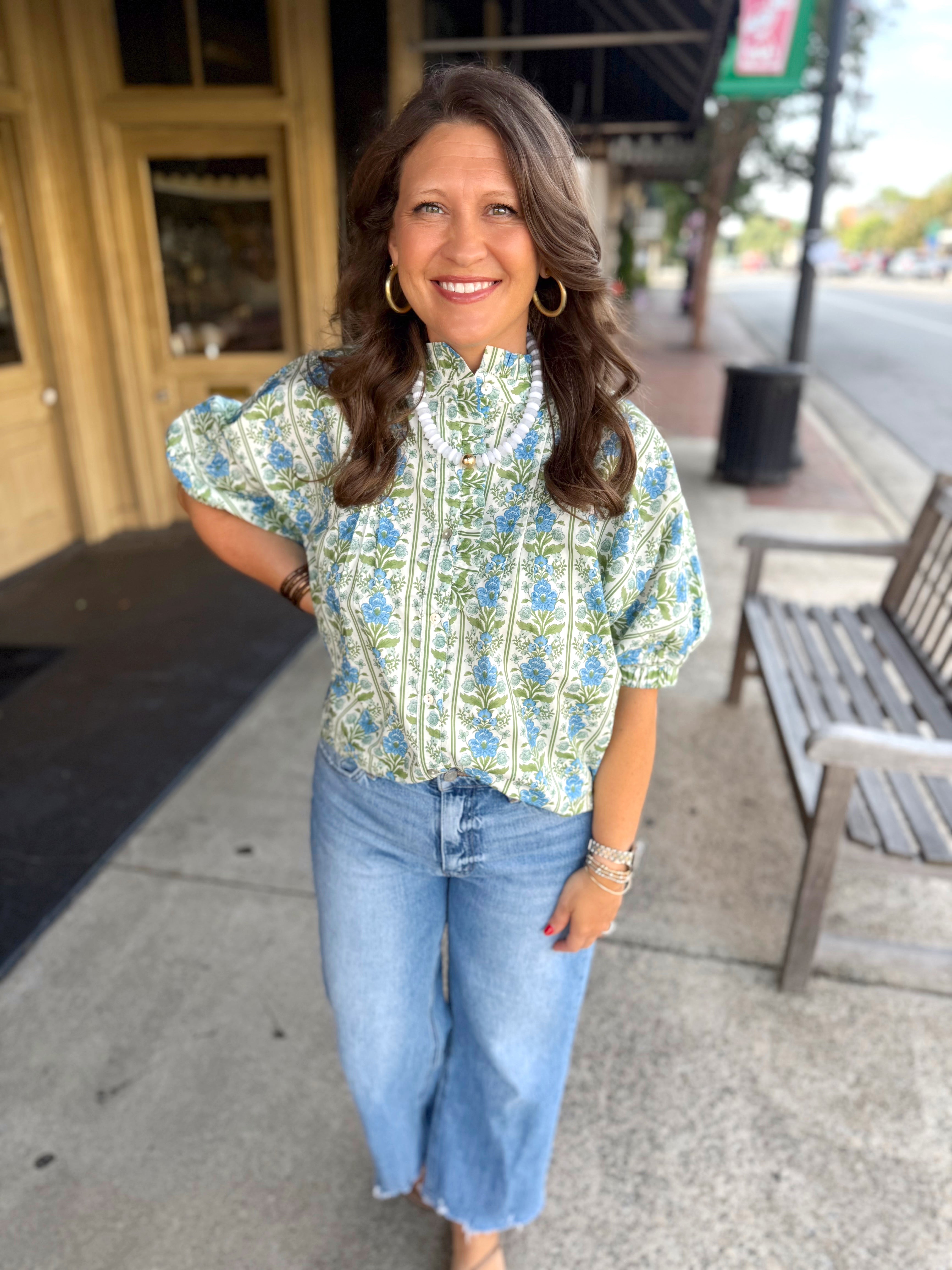 A light green and blue floral patterned blouse with puff sleeves.
