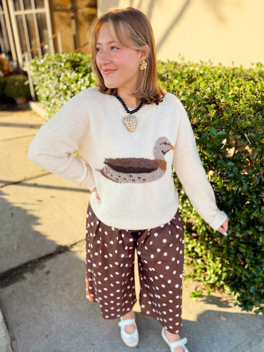 This soft cream knit features a mallard duck design in warm neutral shades of brown, gray, and rust.