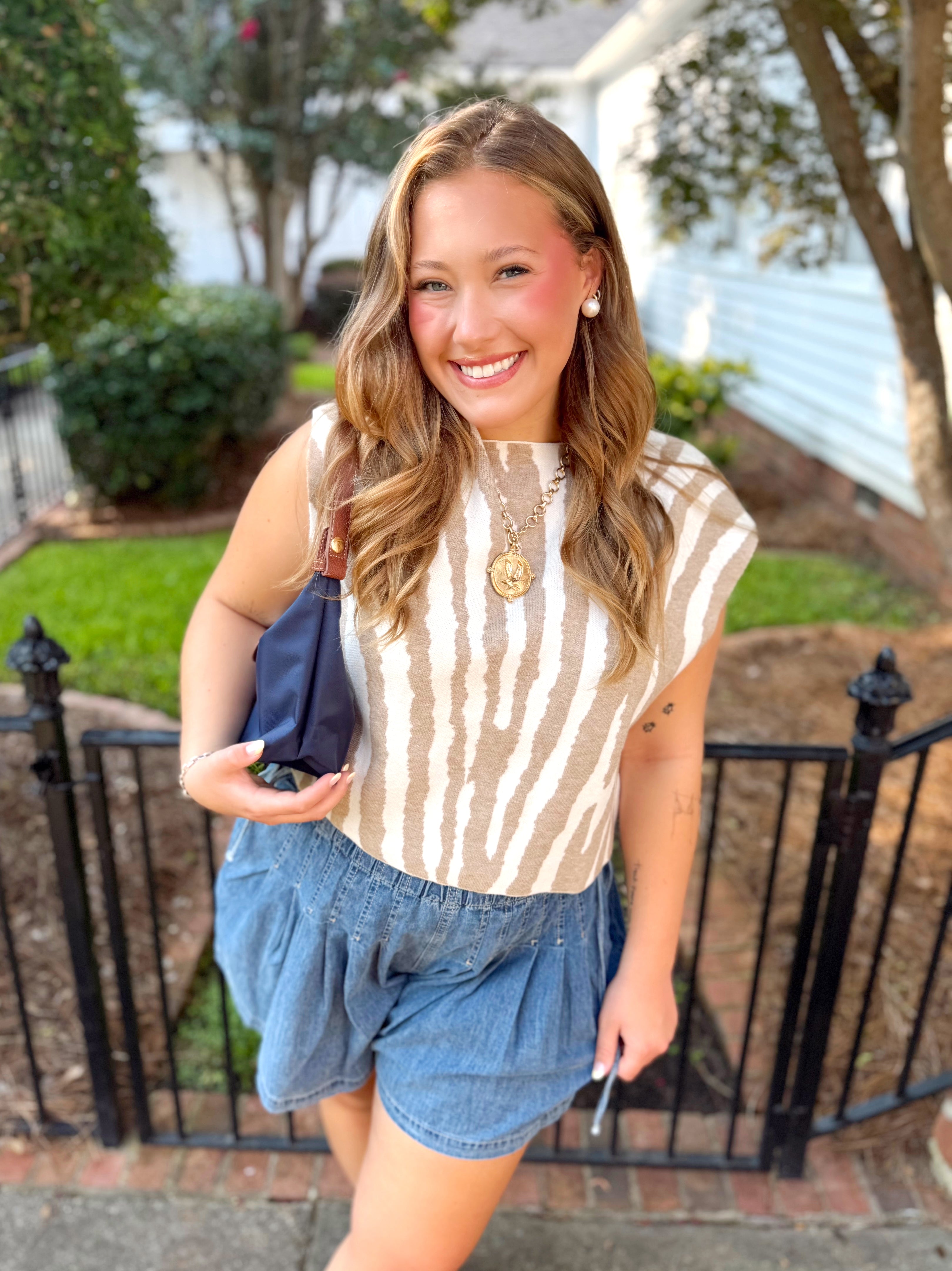 A beige and white vertically striped sleeveless sweater top