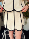 Cream skirt with black trim detailing and a scalloped edging on it