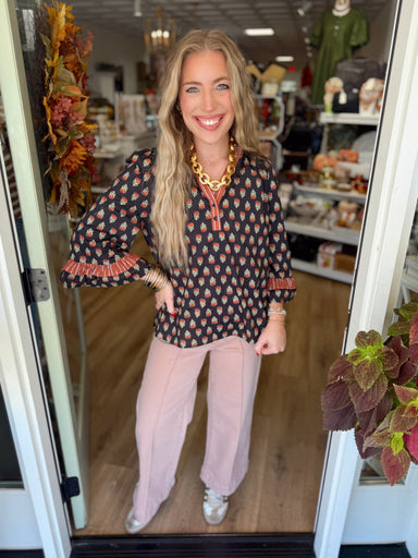 A charming printed top featuring a contrast striped neckline and placket, 3/4 sleeves, and feminine ruffle cuffs.