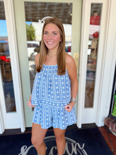 Woman wearing a blue and white floral gingham matching set with a sleeveless flowy top and coordinating shorts.
