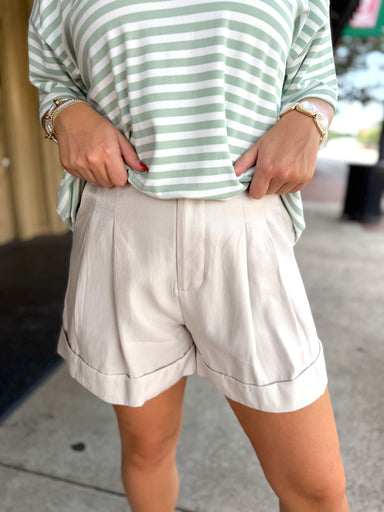 Light beige pleated shorts with rolled cuffs.