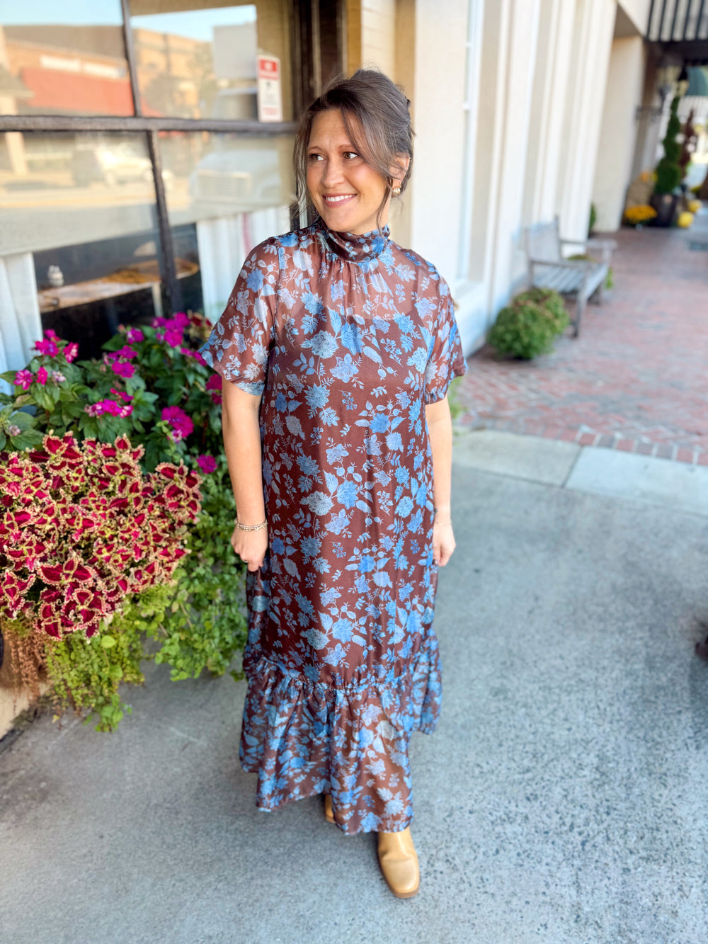 The Chenell Floral Maxi Dress features a warm brown background covered in a beautiful blue floral print for a color combination that feels effortlessly elevated. 