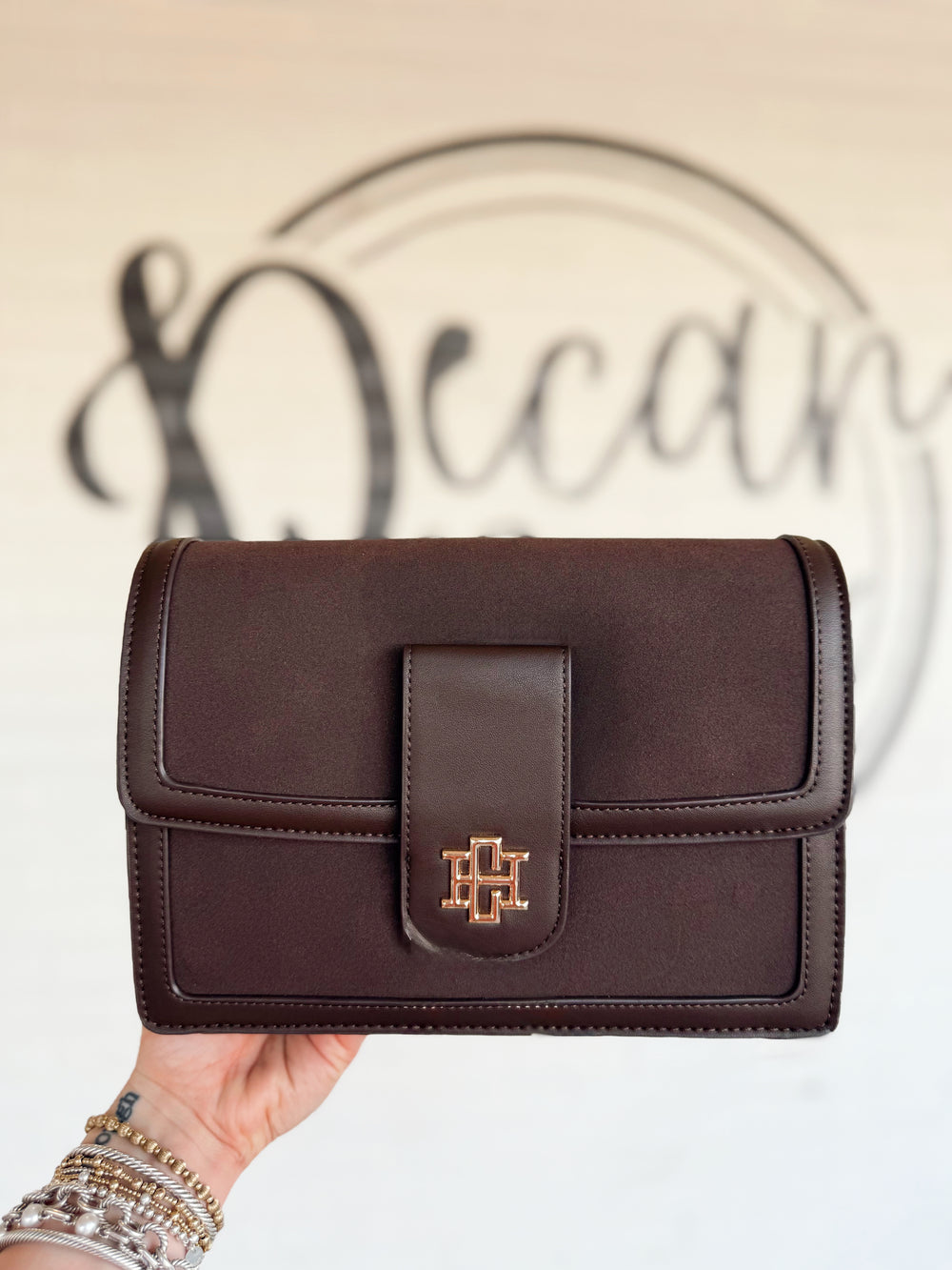 This rich chocolate brown handbag features a structured silhouette with a soft suede-inspired finish and smooth tonal trim. 