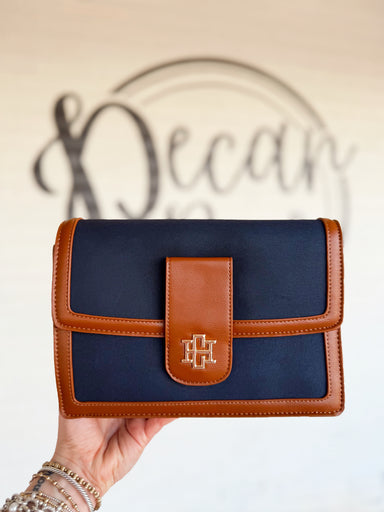 This structured crossbody features a rich navy suede-inspired finish accented with smooth cognac trim for a timeless two-tone look.